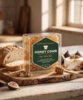 Happy Bees Market 12 oz raw edible honeycomb in a clear clamshell container displayed on a wooden charcuterie board with brie cheese, fresh figs, walnuts, and crusty bread.